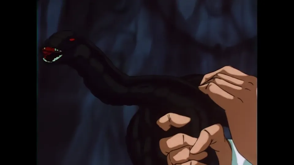 A black serpent held in a bare hand, the frame built so you see the hand first.